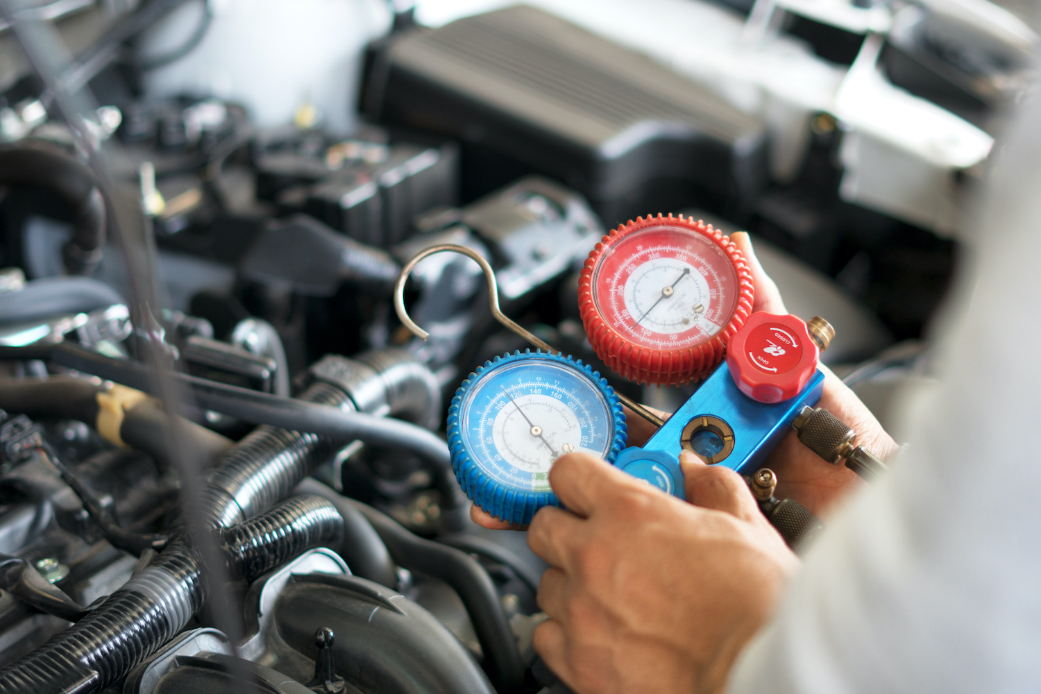 An auto mechanic using an air conditioning inspection tool on a car