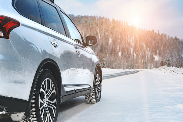 Car driving across a road covered with snow during winter