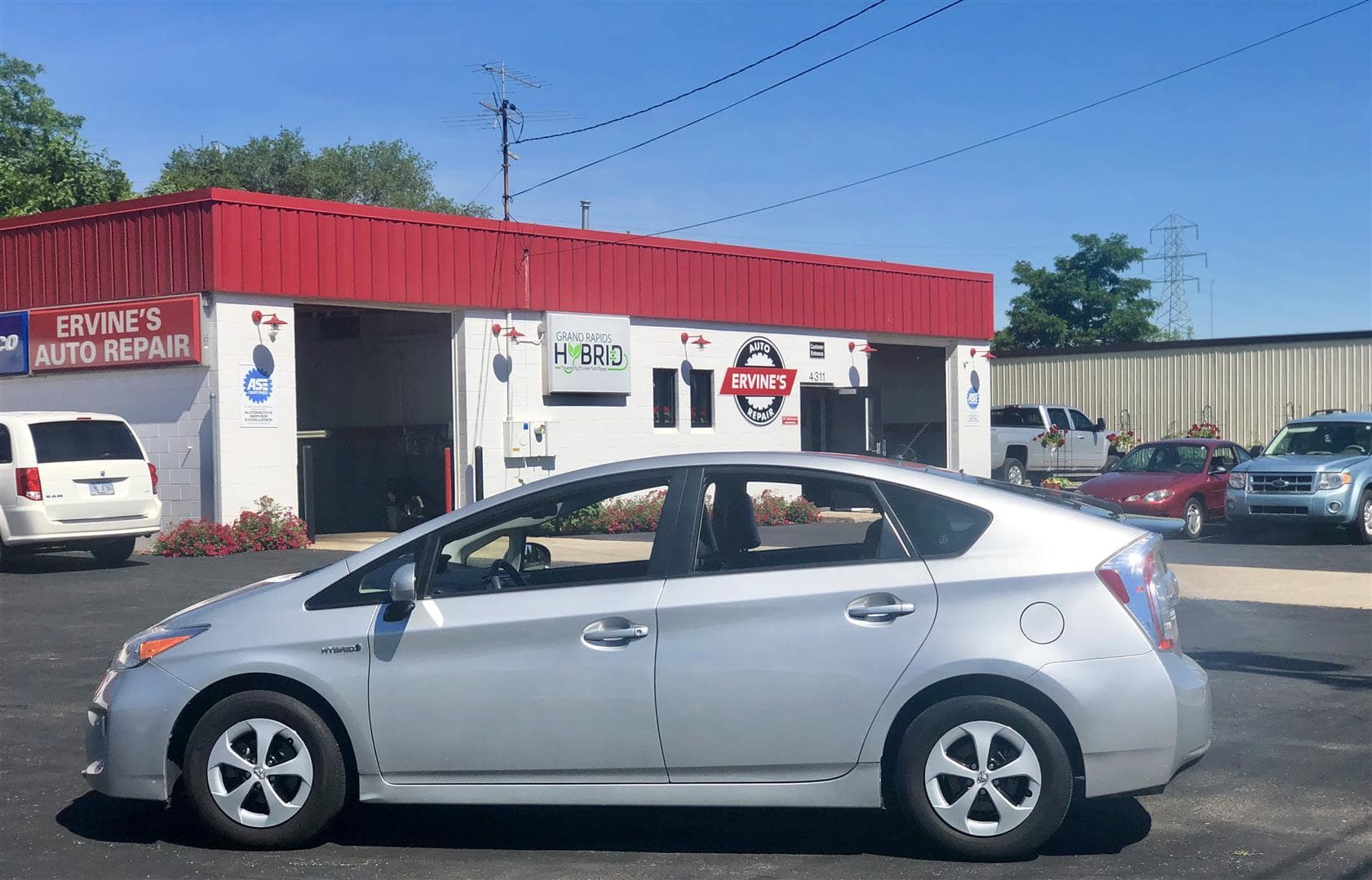 A silver hybrid sedan parked in front of Ervine's Auto Repair